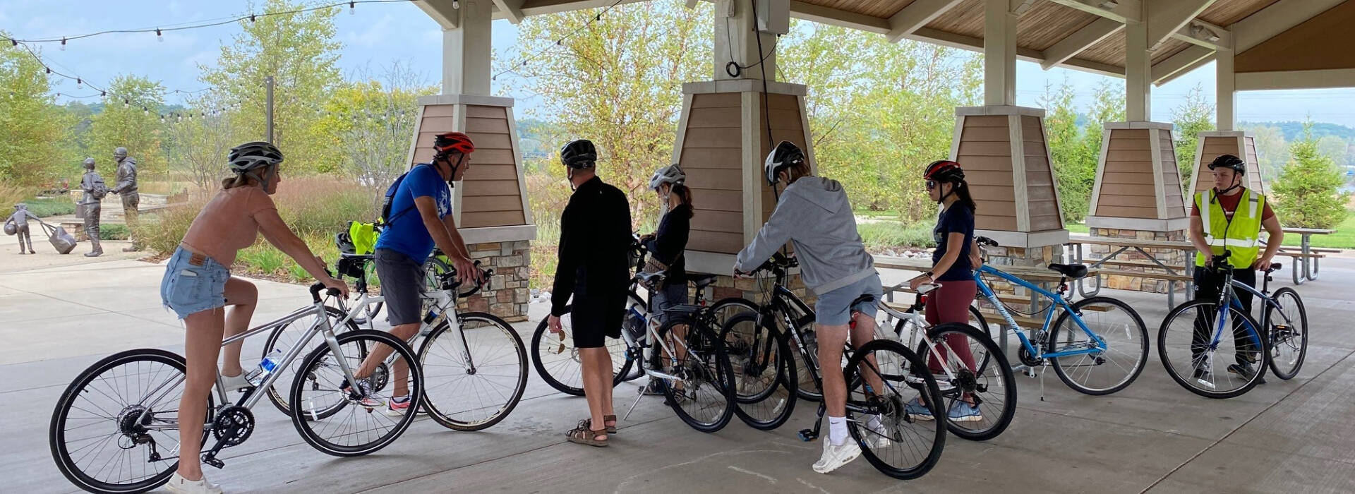 7 participants straddling their bikes as they rest under the Millennium park pavilion